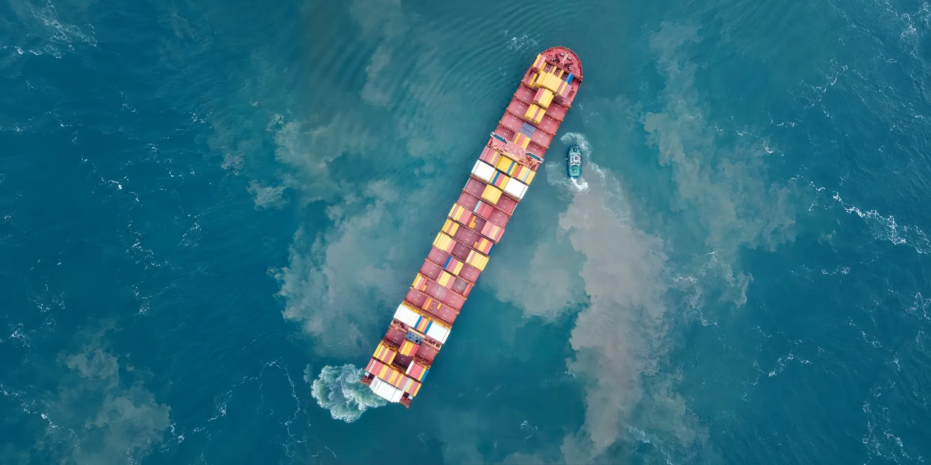 A container ship turning through churned water